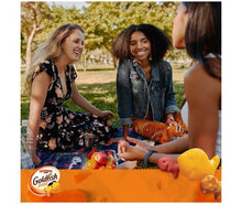 Goldfish crackers variety pack on picnic table while people reach for snacks