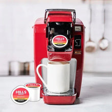 Red Keurig machine with Hills Bros. coffee mug and K-Cup pods