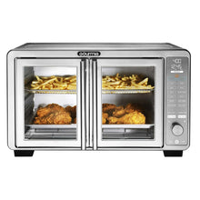 Stainless steel countertop air fryer oven with two cooking chambers; fries and roasts inside.