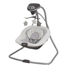 White and gray baby swing with overhead star mobile and cushioned seat