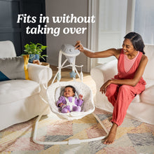 Graco Simple Sway baby swing with baby seated and caregiver beside the frame