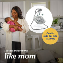 Baby swing with plush gray seat and overhead star toys, standing in home