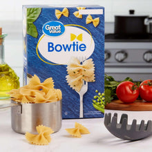 Bowtie pasta box with bowtie pasta pieces, pot, fork, and utensils for serving