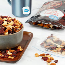 Trail mix bowl with mixed nuts and dried cranberries beside sealed bag