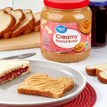 Creamy peanut butter jar with red lid, with bread slices on a plate
