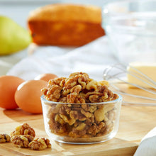Walnut halves and pieces in a clear bowl on a wooden table