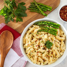 Rotini pasta bowl topped with asparagus and chopped herbs