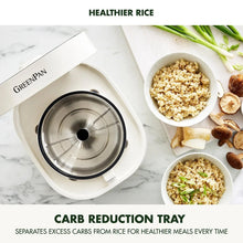 Electric rice cooker with open lid and inner pot, with bowls of rice on counter