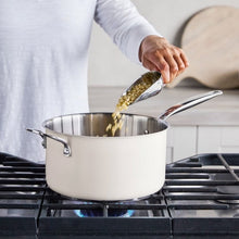 Cream stainless steel popcorn popper pouring popped corn from a glass lid