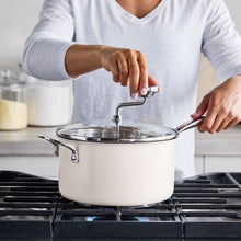 Cream stainless steel popcorn popper on gas stove with glass lid