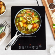 Black induction cooktop under a skillet with soup and visible touch controls