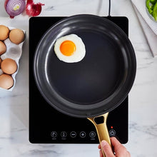 Black induction cooktop with skillet and fried egg, touch control lights