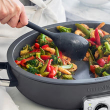Electric ceramic nonstick oval skillet with sautéing vegetables and serving spatula