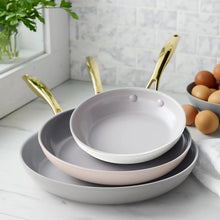 Cream skillet set of three stacked, showing pale interior and gold-tone handles