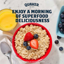 Red bowl of oatmeal topped with strawberries and blueberries