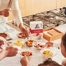 Quaker oatmeal cup and bowls on a kitchen table with ingredients and hands serving