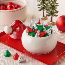 White bowl with foil-wrapped HERSHEY'S KISSES milk chocolate candies in green, red, and brown