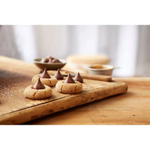 Milk chocolate candies on a wooden board with foil shells, several pieces