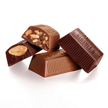 Assorted milk chocolate nuggets with nuts, broken pieces and whole bars on white