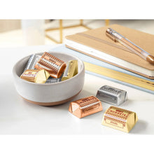 Assorted chocolate nuggets in gold and brown wrappers, with pieces beside a bowl