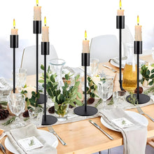 Black metal taper candle holders with round bases and tall slim candle cups