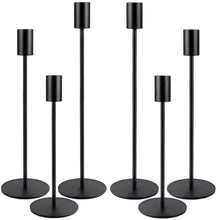 Black metal taper candle holders with cylindrical top cups and round weighted bases.