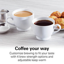 Coffee serving set with two cups and spoon next to a carafe, ready for brewing
