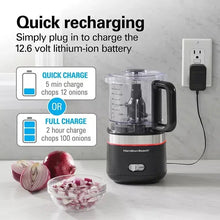 Cordless food chopper on countertop with charging cable connected to the base