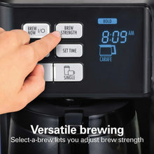 Black coffee maker control panel with hand pressing brew buttons