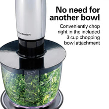 Chopping bowl filled with blended green herbs and a stainless hand blender