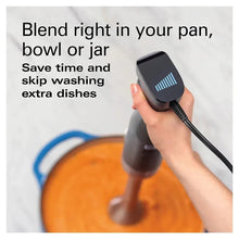 Hand blender with black speed control, held above a mixing bowl