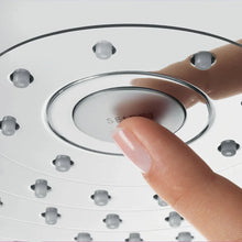 Showerhead face with water outlets and finger pressing a control button