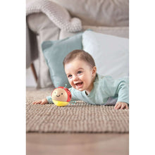 Baby smiling while playing with a red ladybug rattle on a mat