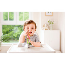Infant holding flower light-up rattle with smiling face; colorful petal ends
