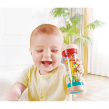 Rainbow bead shake rattle in baby hands, clear tube with red cap and teal base