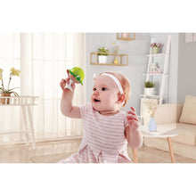 Infant holding a green turtle stay-put rattle toy with suction base