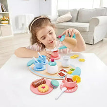 Child playing with pastel toy tea set on a table: teapot, cups, plates