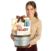 Gift basket in a tin with ribbon bow; assorted cookies and chocolate held by person