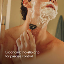 Orange handled 5-blade shaving razor cutting through lather on face