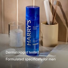 Blue facial toner bottle with cap, shown standing beside bathroom items