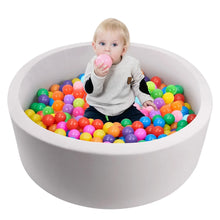 Gray foam ball pit filled with multicolor balls, baby holding a pink ball