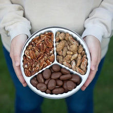 Open pecan tin held in hands, with chocolate-coated, praline, and roasted salted pecans