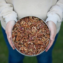 Hand-held bowl filled with roasted salted pecans