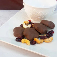 Milk chocolate cranberry cashew caramels on plate with dried fruit and nuts
