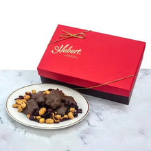 Milk chocolate cranberry cashew caramels on plate beside red gift box