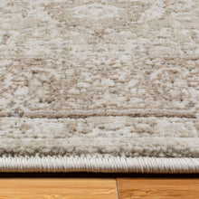 Beige area rug close-up with plush texture and subtle distressed pattern, border edge.