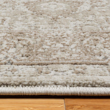 Beige area rug close-up with textured pile and subtle distressed scroll pattern