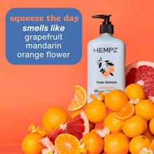 Hempz Triple Moisture body lotion bottle with black pump beside citrus fruit, light blue