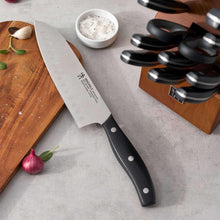 Chef knife with black handle and white dots, beside a wooden knife block