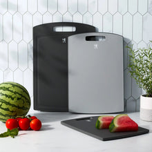 3-piece dark gray cutting boards with handle cutouts; watermelon and tomatoes on top